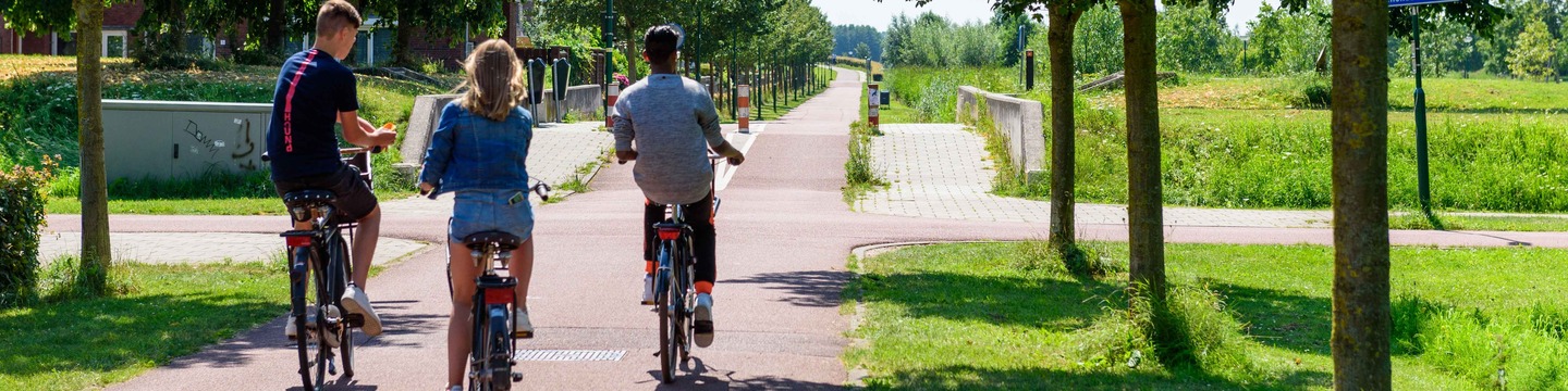 Fietsende jongeren door park Schoneveld